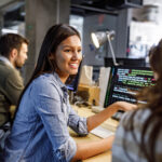 Happy female programmer talking to her colleague in the office.